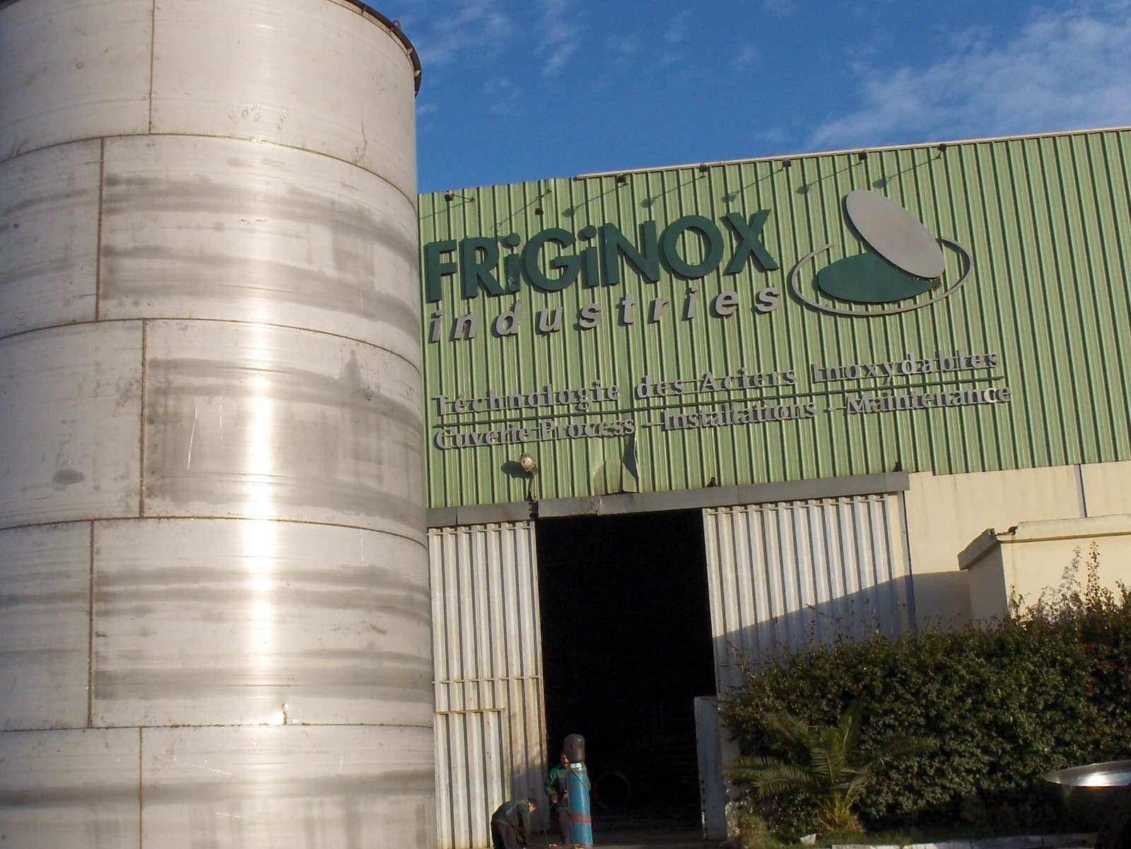 Un réservoir vertical en acier inoxydable dressé devant la façade de l’atelier Friginox