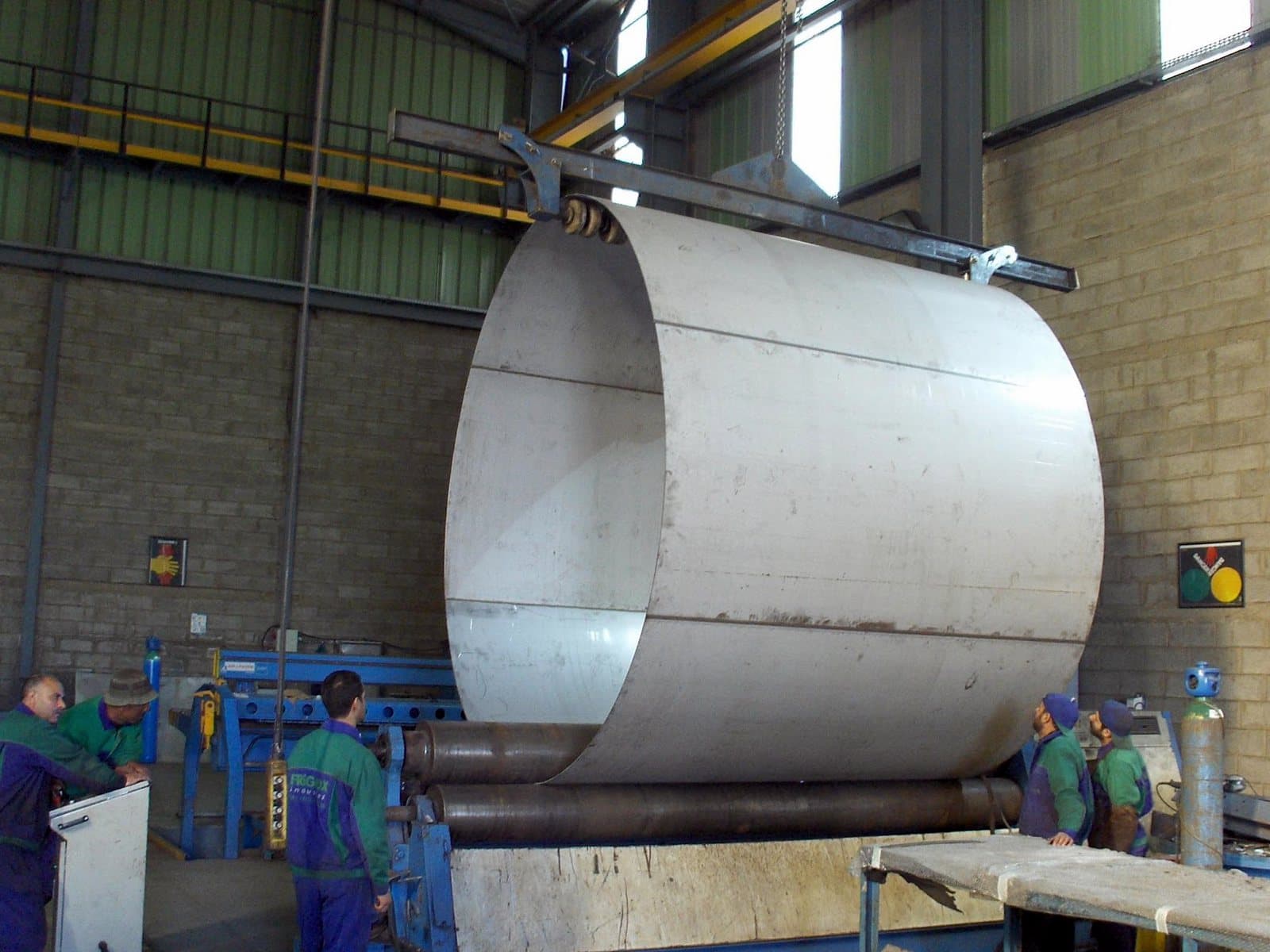 Grande virole en acier inoxydable en sortie de rouleuse dans l’atelier Friginox, guidée par l’équipe de part et d’autre