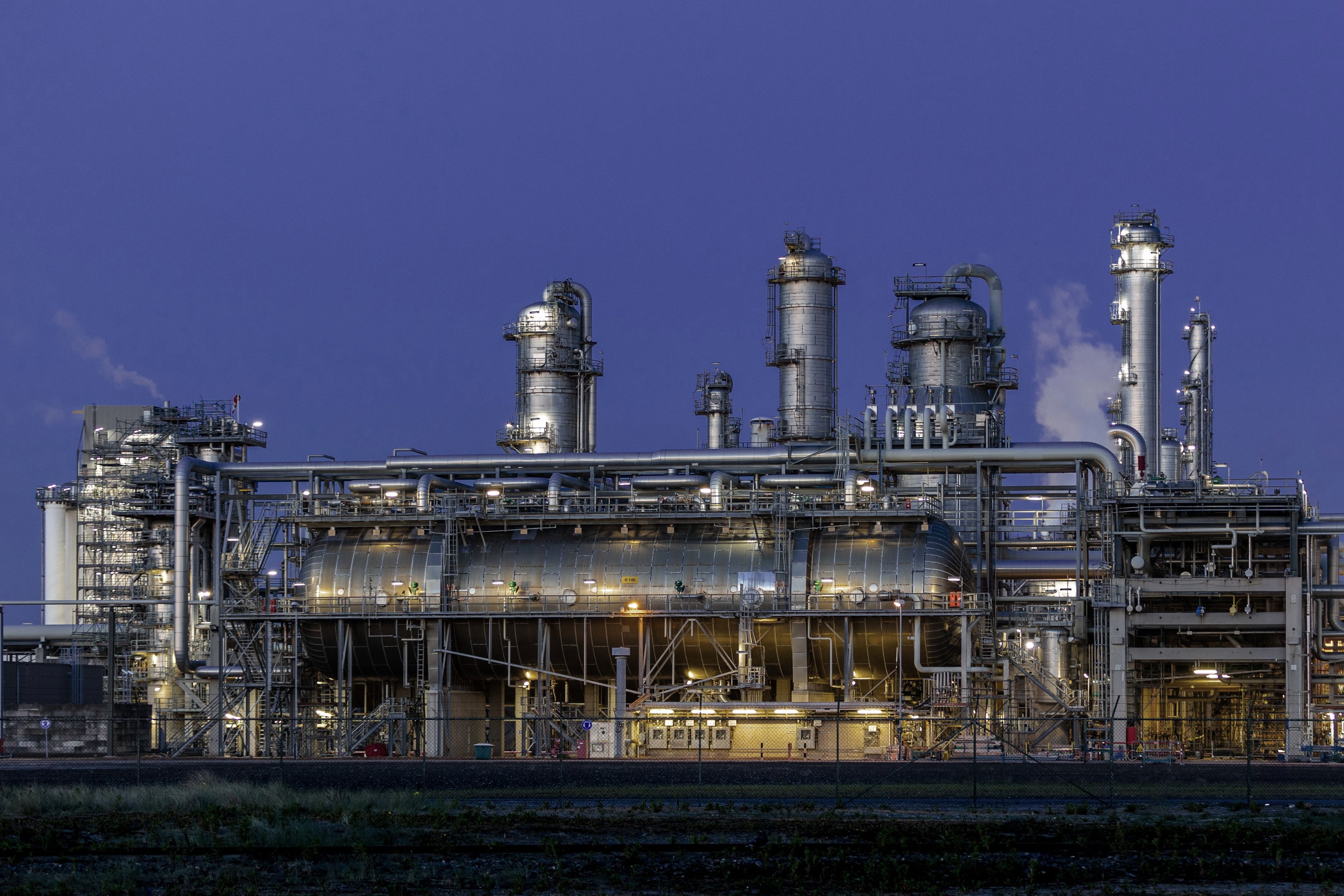 Unité de procédé d’une raffinerie à l’heure bleue, avec colonnes de distillation, appareil à pression horizontal et racks de tuyauteries